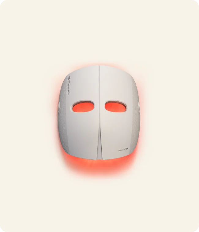 White Therabody TheraFace Mask with illuminated red LEDs